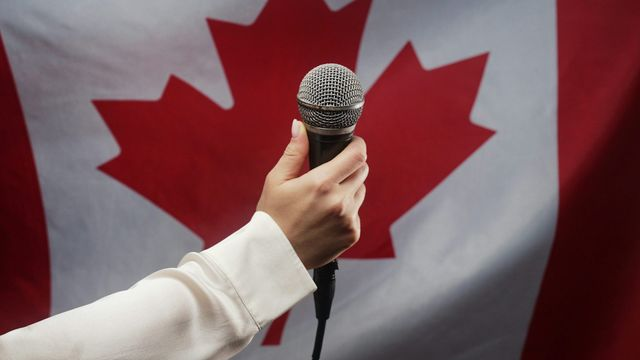 photographie d'un micro devant le drapeau du Canada