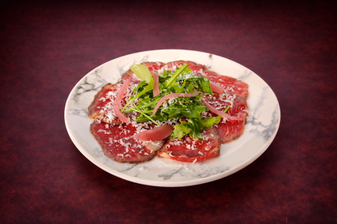 經典義式生牛肉薄片（Beef Carpaccio）｜1884 Taipei 開胃菜，NT$ 280・薄切生牛肉鋪陳盤面，佐芝麻葉微苦清香與帕瑪森起司鹹香，口感細緻優雅。

過敏原: 奶類