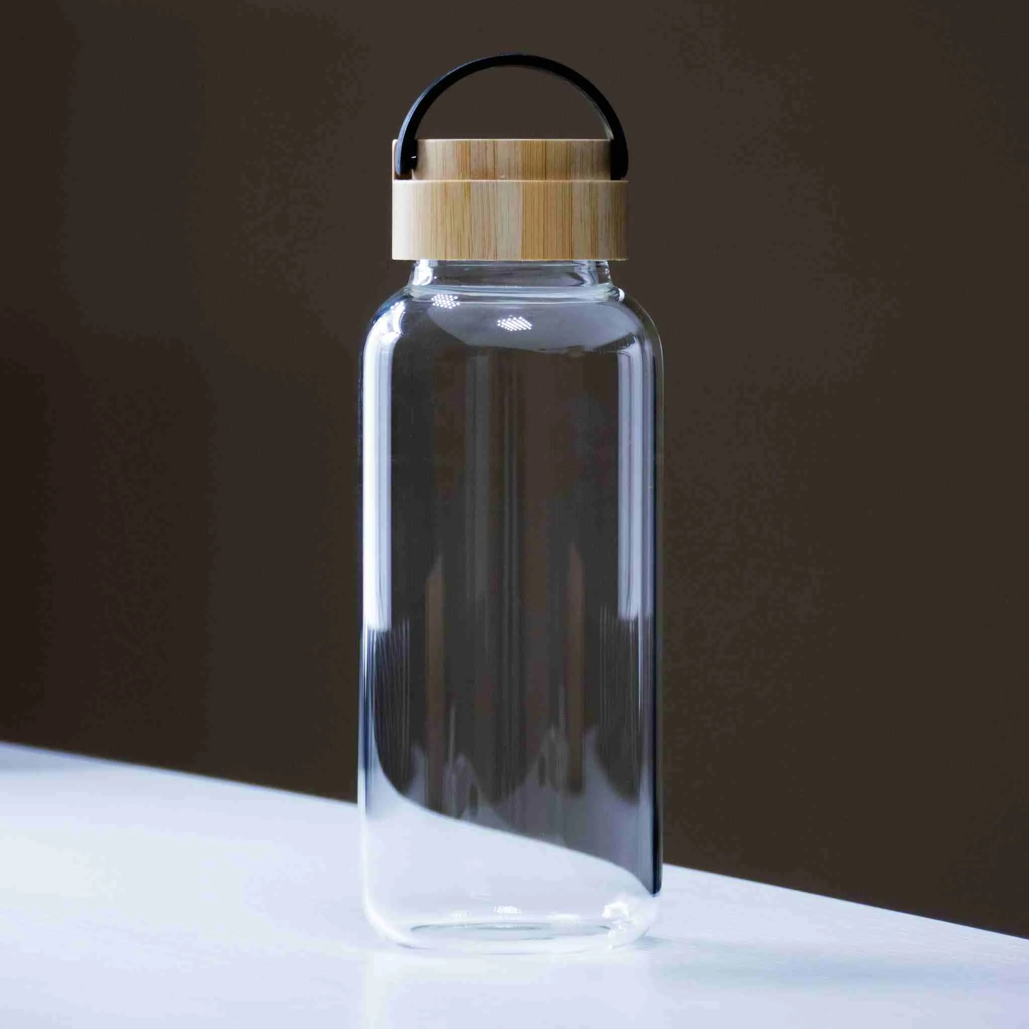 Side view of jute-wrapped glass bottle showing black trim edge and clear upper body
