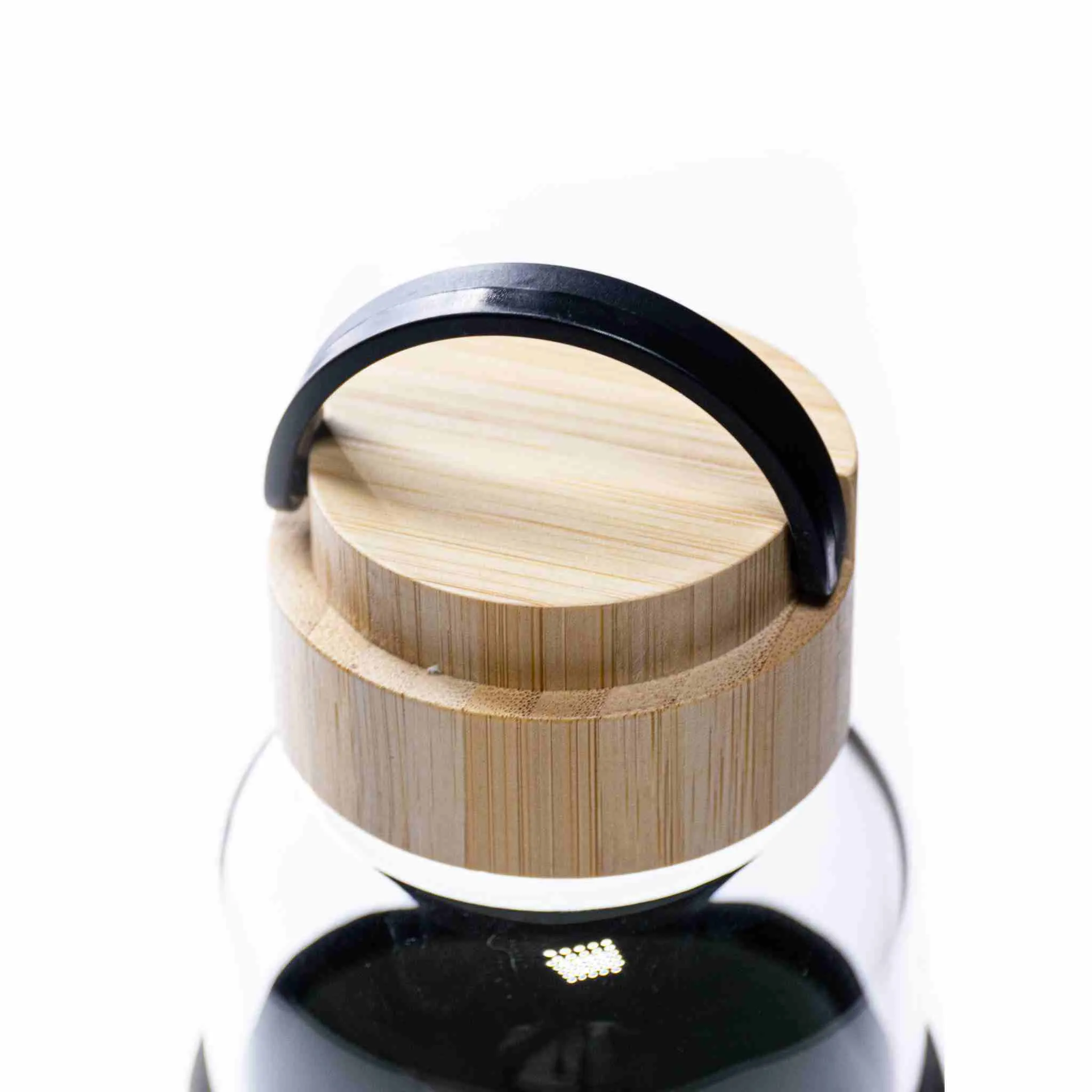 Close-up of bamboo screw-top lid with black carry handle on a glass bottle