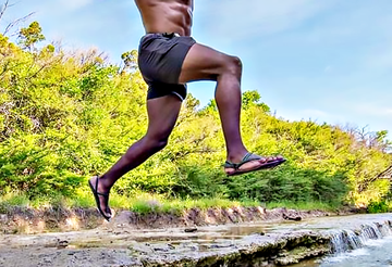 A shirtless man wearing Elemental barefoot shoes jumping