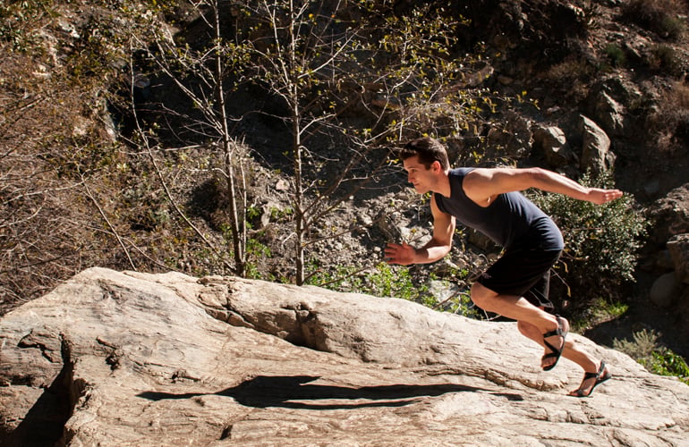 A man running on rocks wearing barefoot sandals