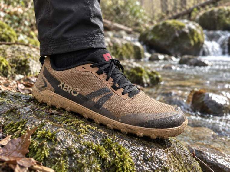 Adam wearing the Mesa Summit on wet rocks beside a river during testing