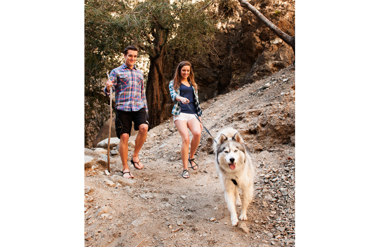 A couple wearing barefoot shoes walking a dog