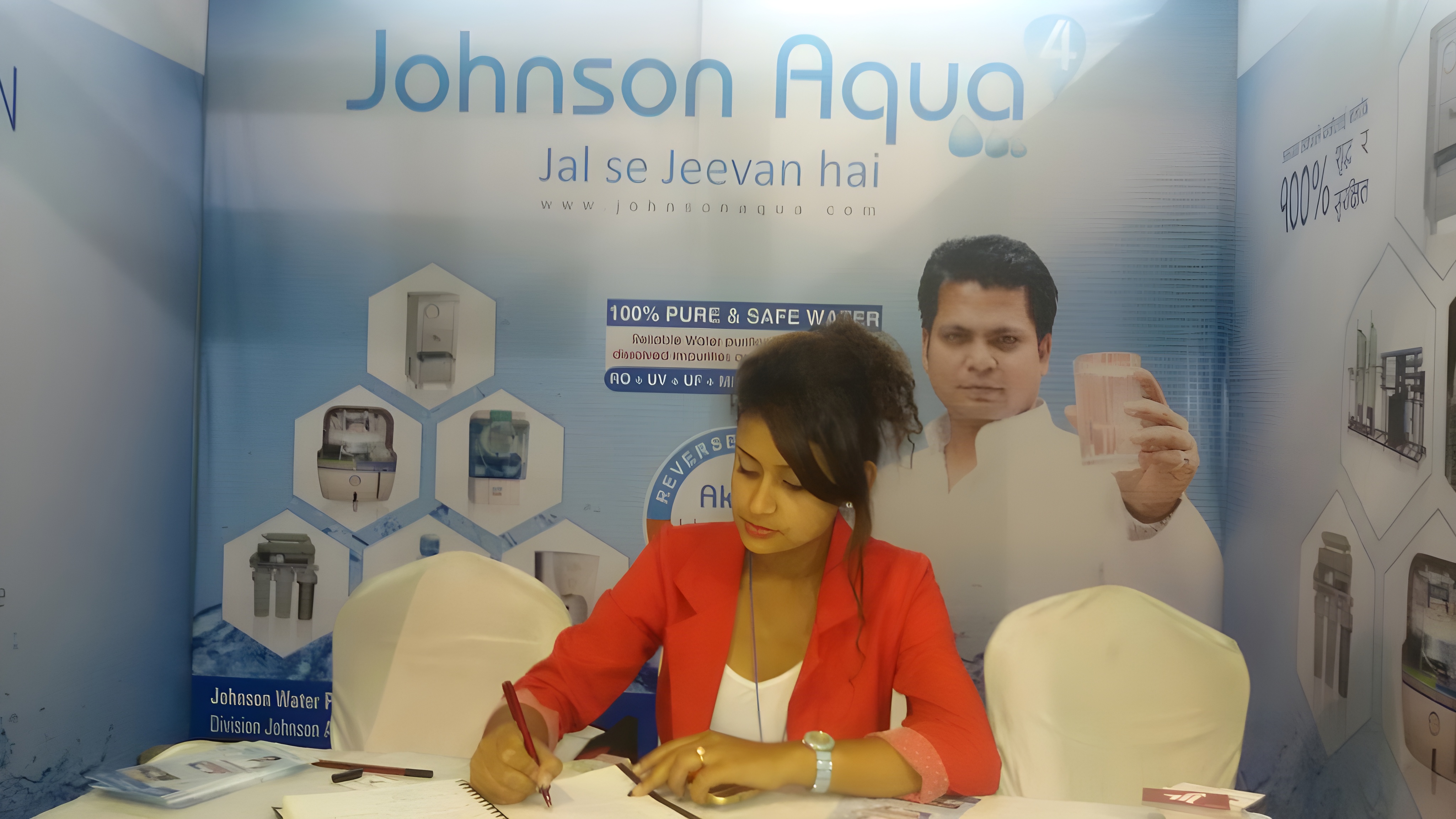 A promoter at the Johnson Aqua stall with Rikesh Karna's brand ambassador backdrop.