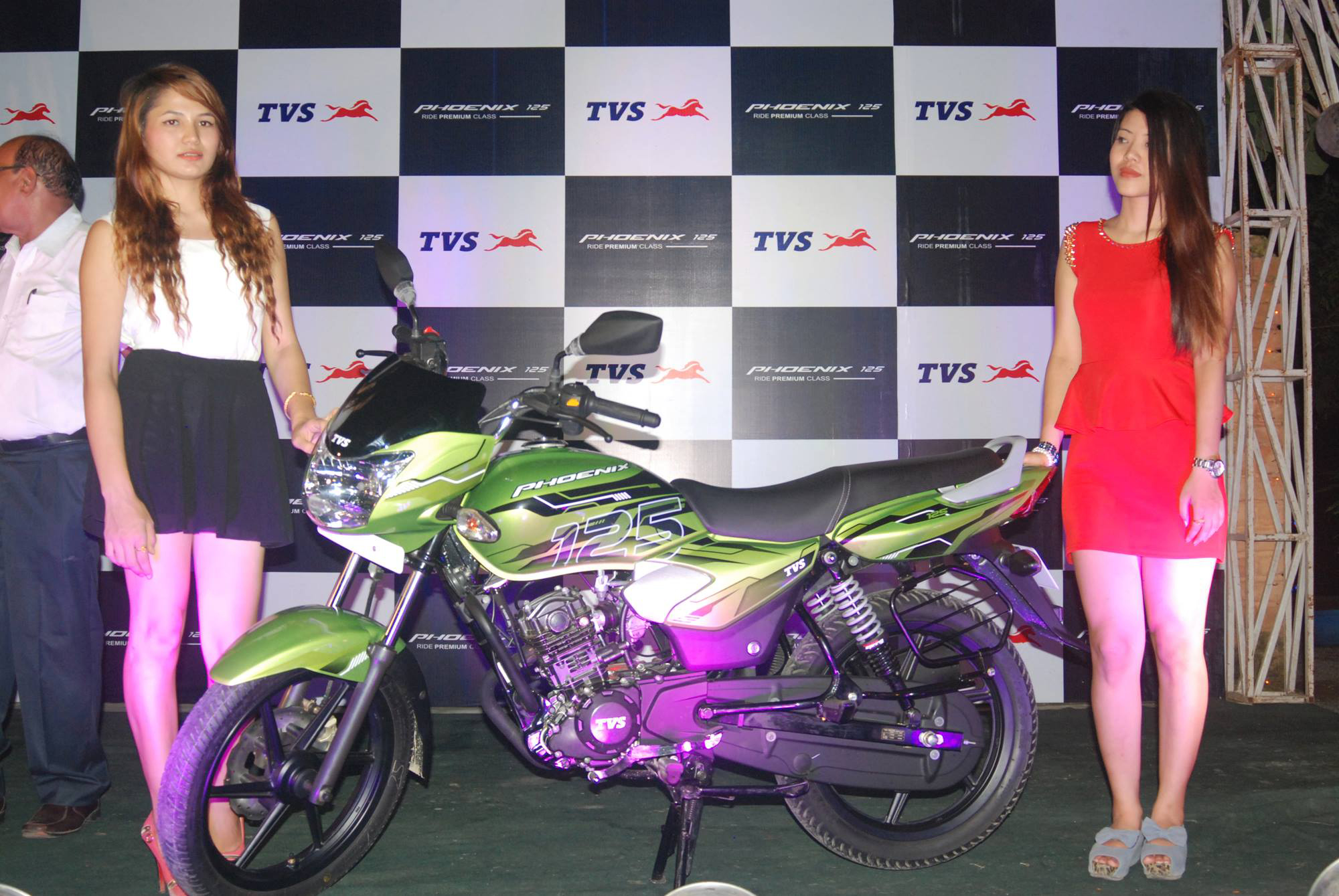 Ushers posing with the newly launched TVS Phoenix bike on stage.