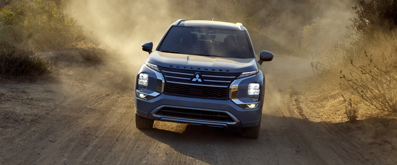 Vue avant du Mitsubishi Outlander 2025 en puissance sur route de sable