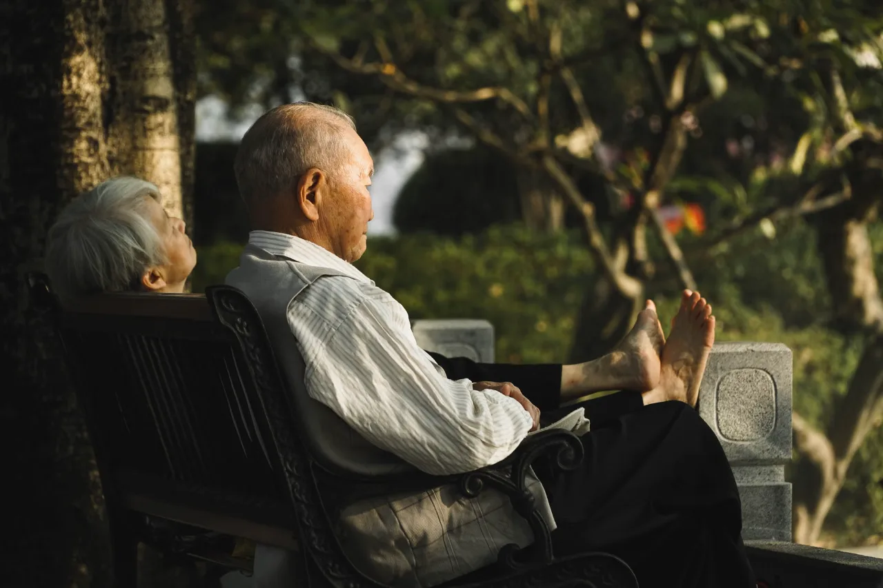 Senior couple enjoying a peaceful afternoon on a bench in a serene park.