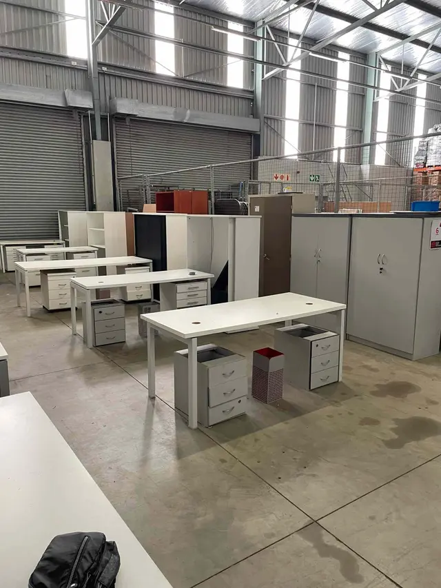 LARGE QTY OFFICE FURNITURE: 4 X WHITE STEEL DOUBLE OFFICE TABLES, 2 DOOR STEEL STATIONARY, CUPBOARD,STEEL FILING CUPBOARD, 1 X STEEL WHITE TABLE, SLIDING DOOR CREDENZA, 2 X WHITE PEDESTALS & DUSTBIN (x5 EACH), 2 X WOODEN SHELVING UNITS, 2 X WOODEN STATIONARY CUPBOARDS, PIGEONHOLE SHELVING UNIT, ROUND STEEL TABLE & POT PLANT ETC