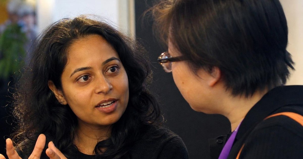 Diverse adults in close conversation at an Australian AI community gathering, listening with trust and focus