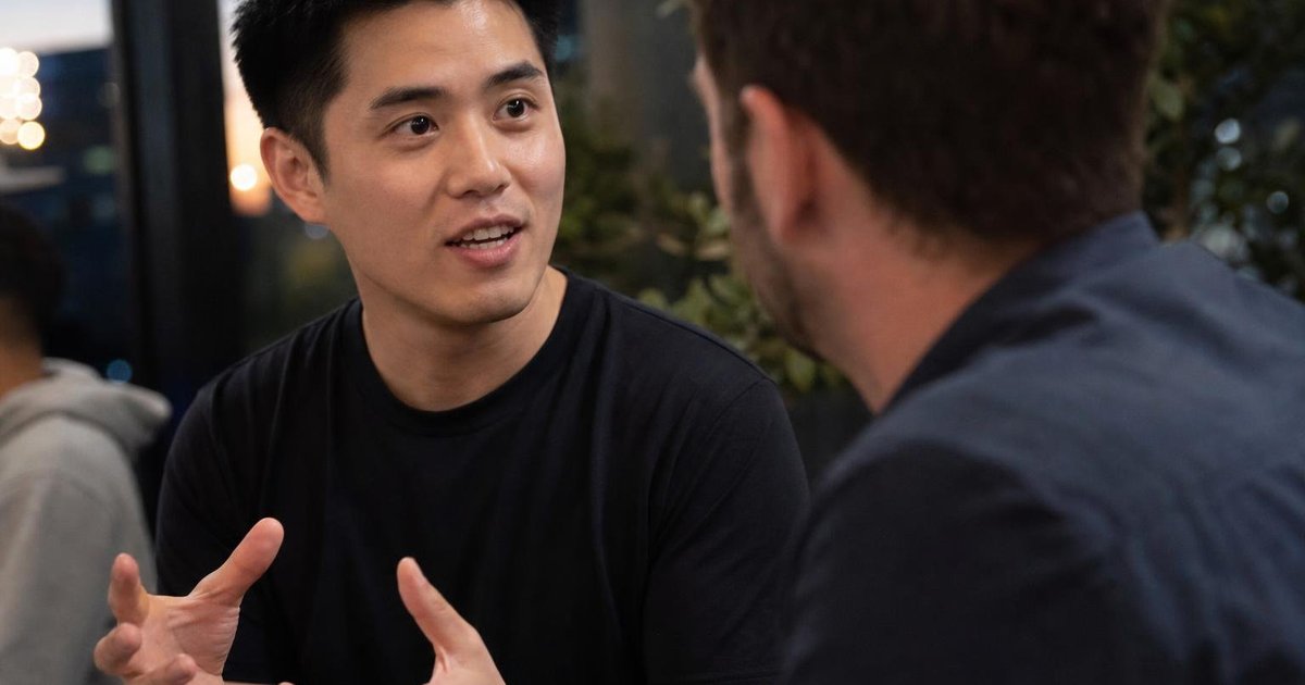 Close-up candid of Sydney tech meetup attendees networking over laptops at an AI startup event