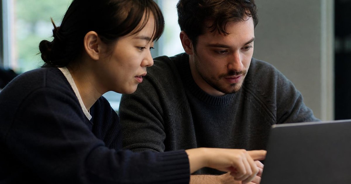 Close-up of teammates mapping AI intelligent agent decisions on a laptop in a candid workshop moment