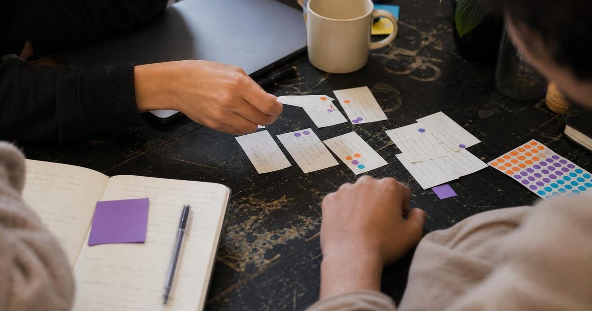 Founders sort customer feedback cards beside notes and coffee during a candid product-priority review