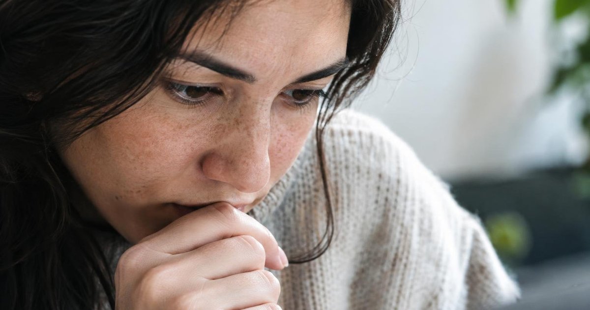 Close-up of a person looking down with a hand near the face.