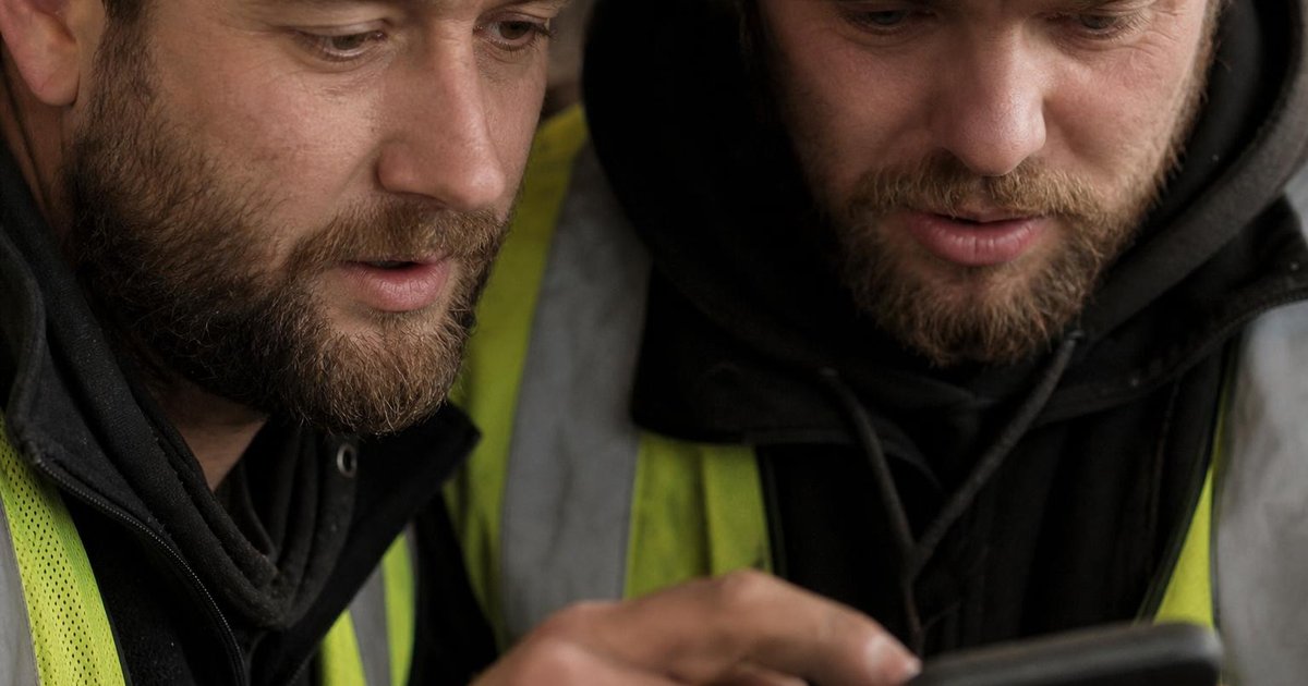 Builder’s hands using an AI estimating app on a dusty worksite tablet in Australia