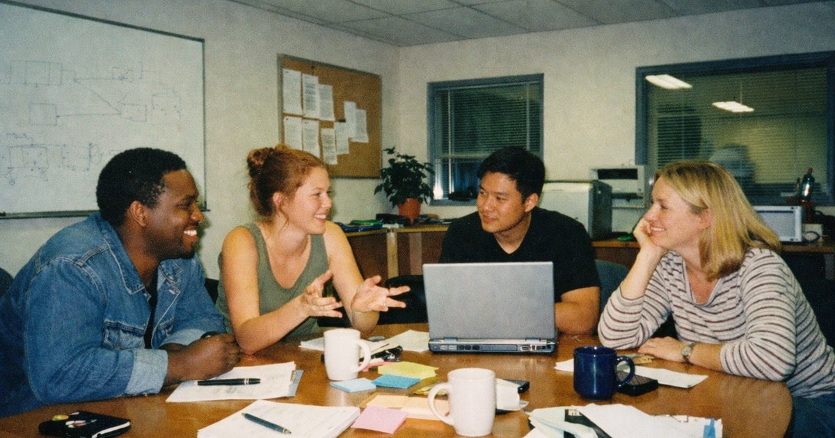 Group of diverse individuals brainstorming in a retro-tech workspace, capturing the vibrant 90s startup vibe.
