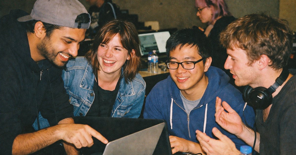 People in a 90s-inspired tech startup setting brainstorm and collaborate over laptops and coffee.