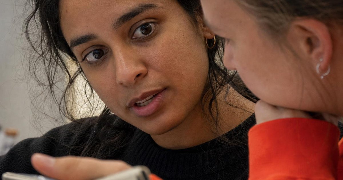 Two colleagues comparing missed follow-ups on a phone, absorbed in a candid close-up conversation