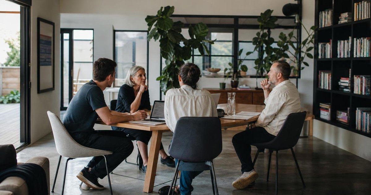 Small startup team reviewing customer workflow notes and AI assumptions on a whiteboard in a casual office