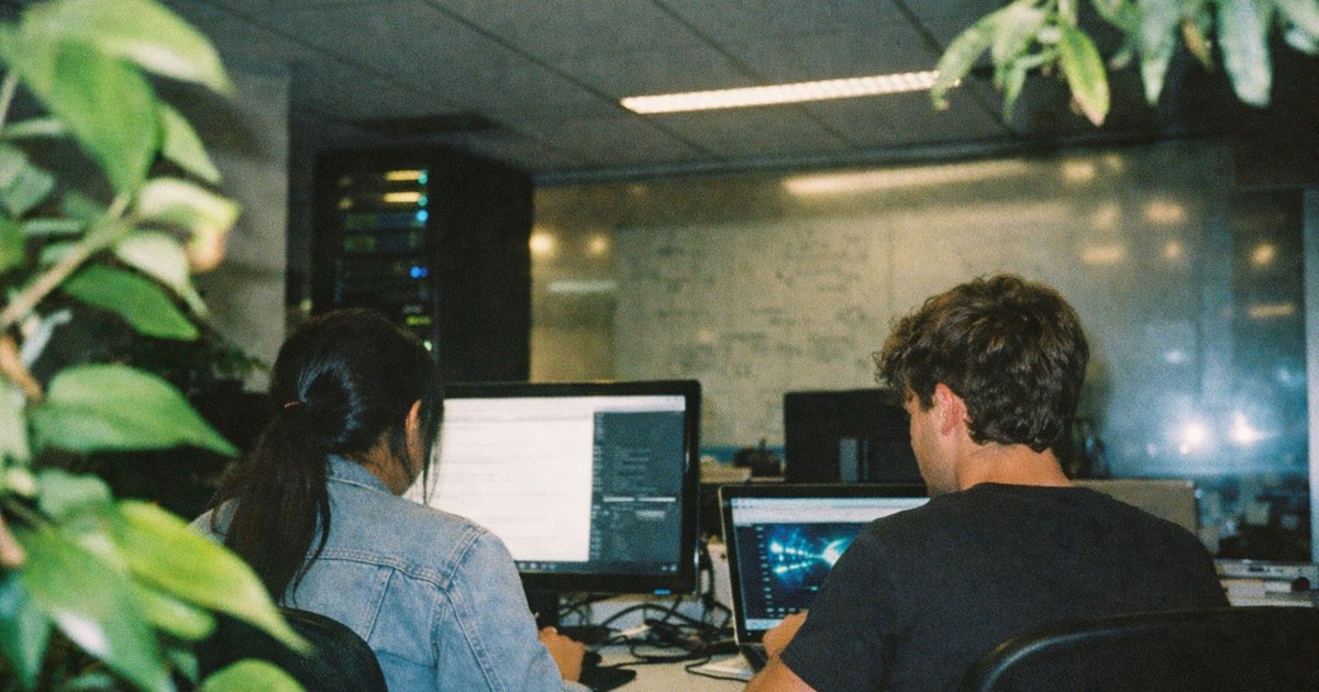 Diverse team collaborating in a trendy tech workspace, showcasing 90s film aesthetics and innovation.
