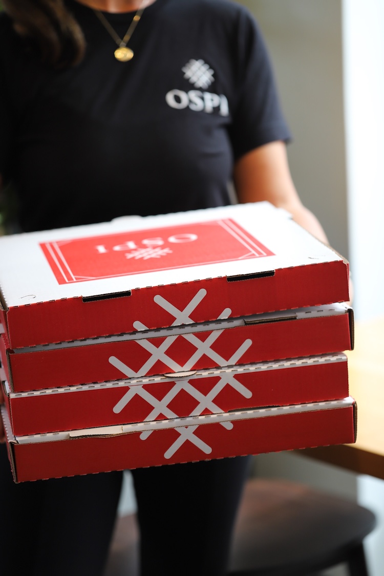 Several Ospi-branded pizza boxes.