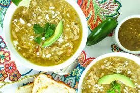 Vibrant green chile stew in rustic bowl, warm New Mexico light, inviting aroma.