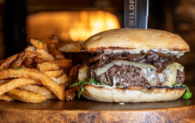 Juicy Aspen bison burger, warm mountain lodge ambiance, culinary adventure.