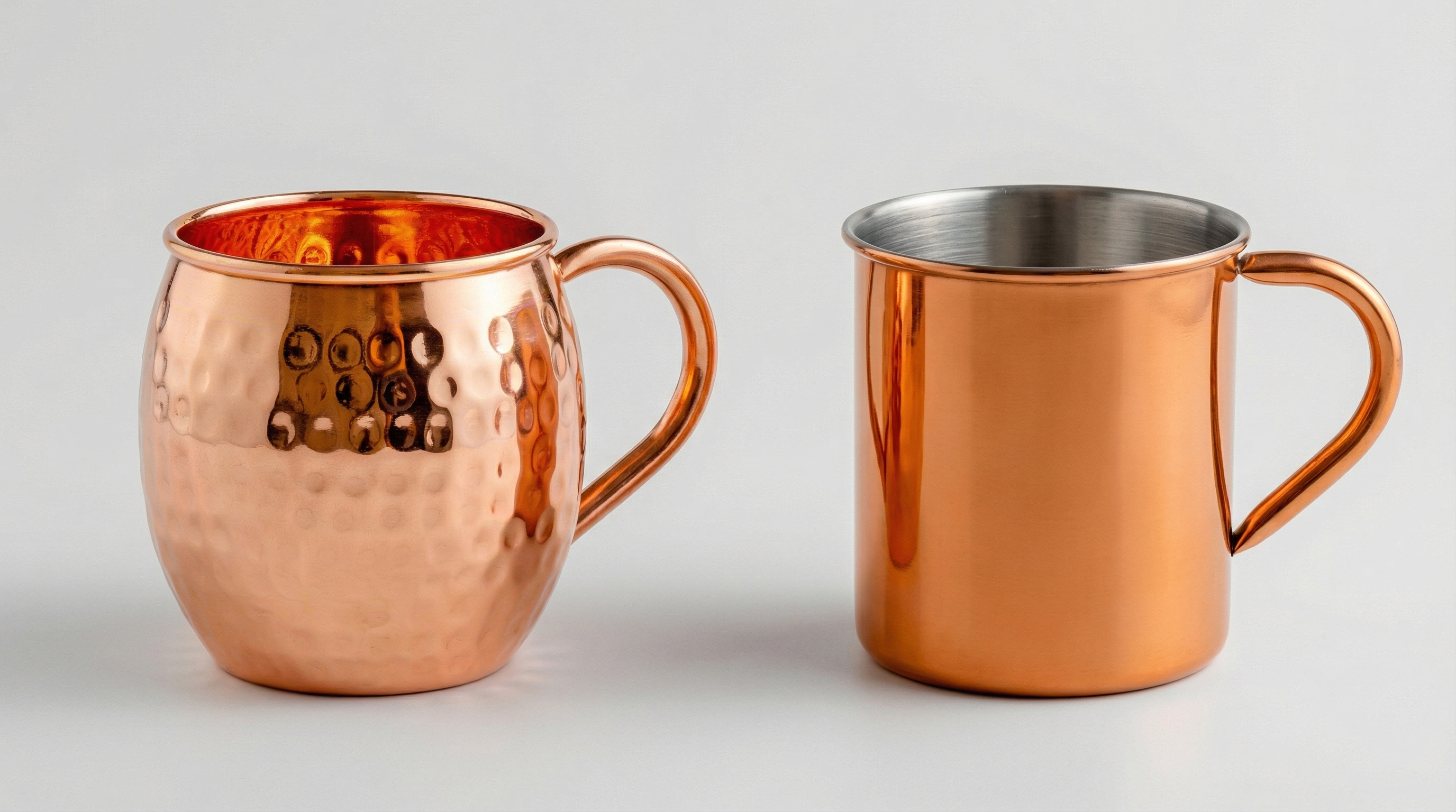 An educational, side-by-side comparison studio shot of a real, solid hammered copper mug next to a cheap, smooth stainless steel imitation mug with copper plating. The real mug has a rich, warm rose-gold color and visible texture. The fake mug looks flat and slightly orange. Neutral, light grey background, clear visual contrast, studio lighting, macro photography.
