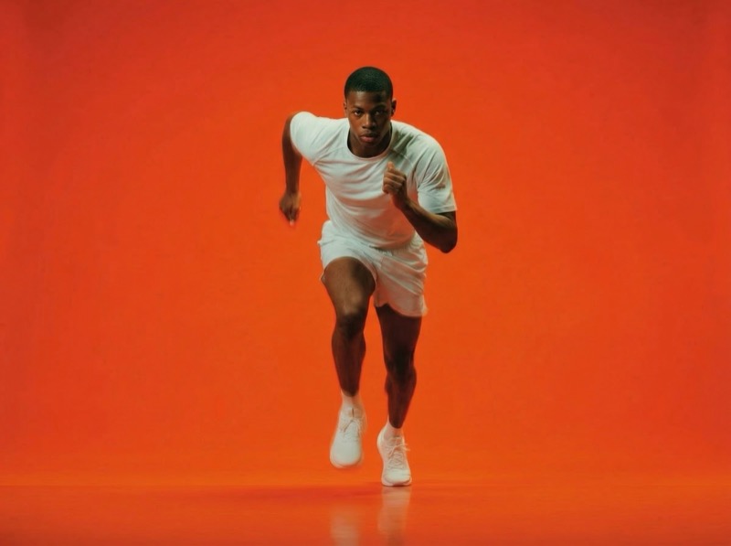 Athlete sprinting in white on orange backdrop