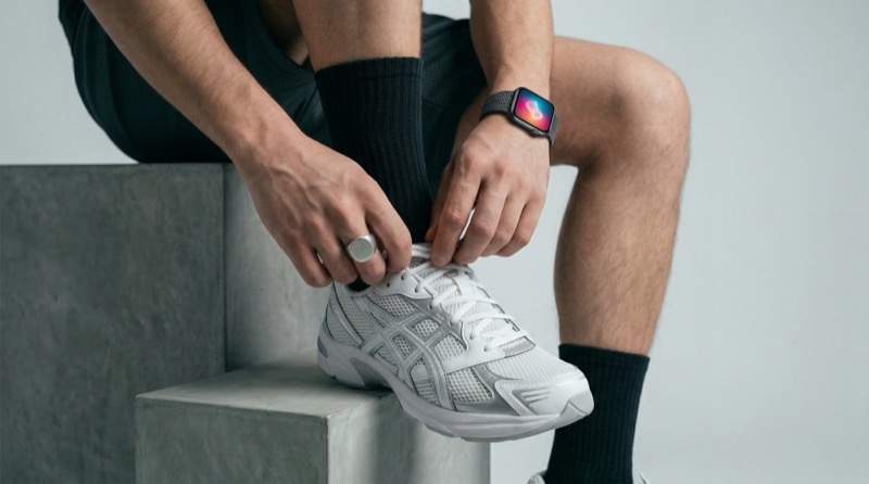 Athlete tying running shoe with smartwatch