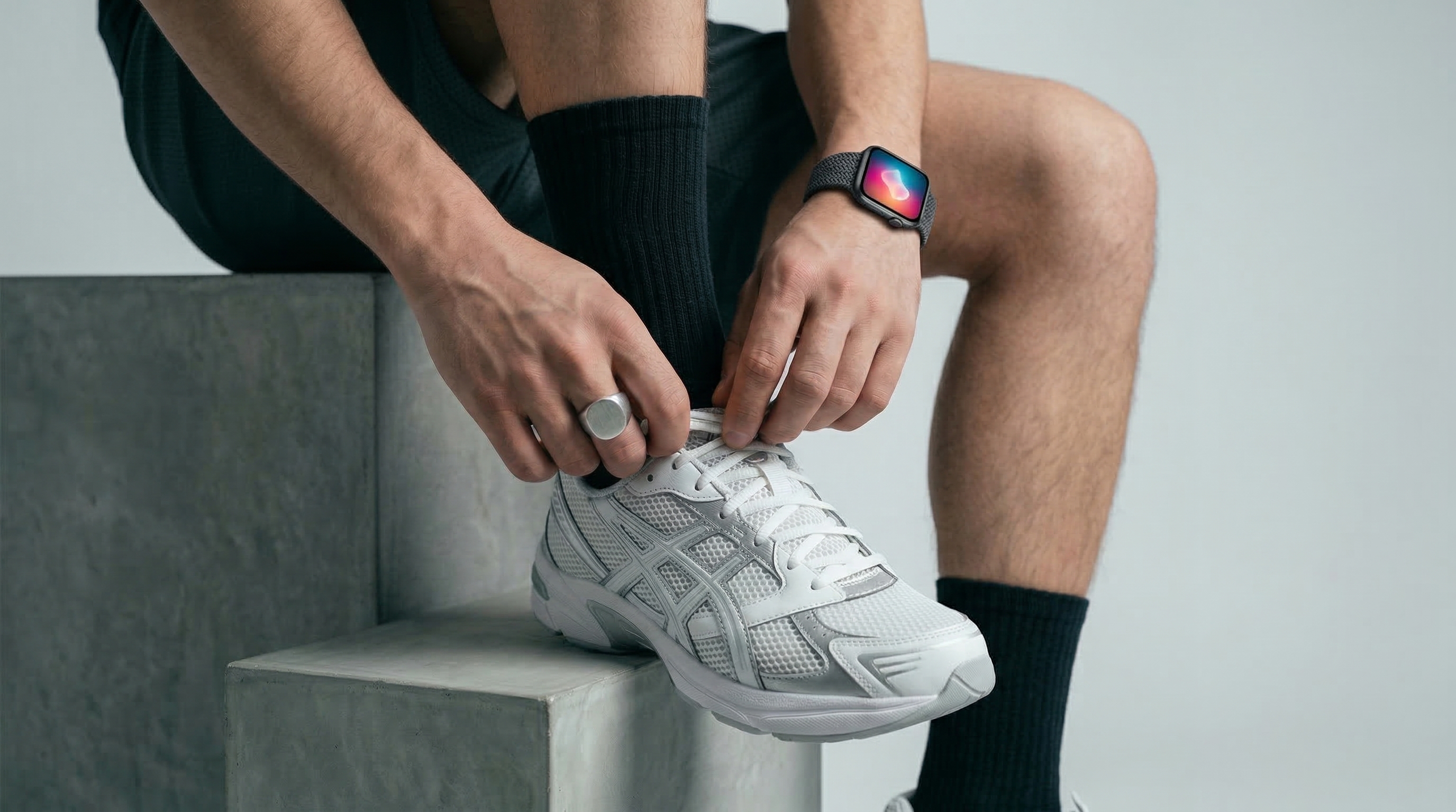 Athlete tying running shoe with smartwatch