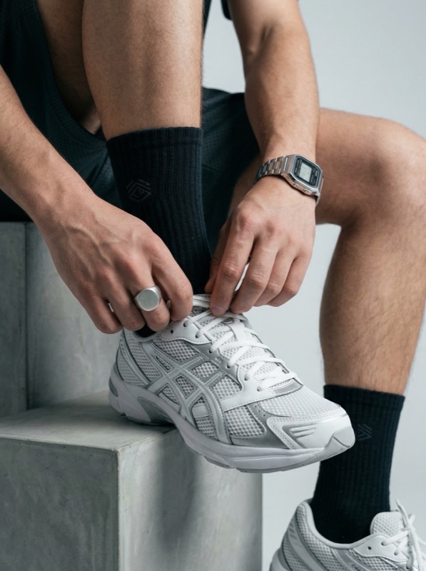 Athlete tying white running shoe indoors