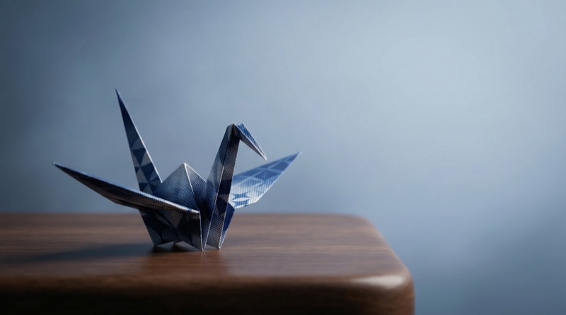 Blue origami crane on wooden table