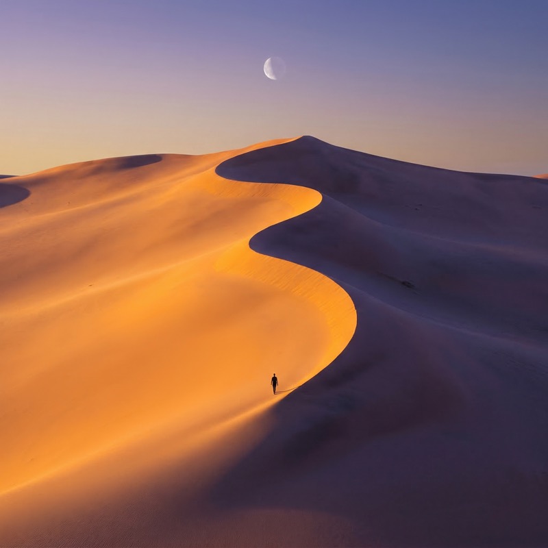 Lone Hiker on Desert Dunes at Twilight
