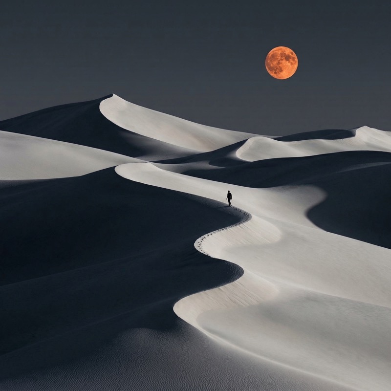 Lone hiker on sand dunes under a full moon