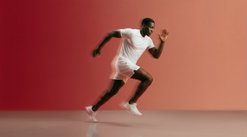Male athlete sprinting in studio with red backdrop