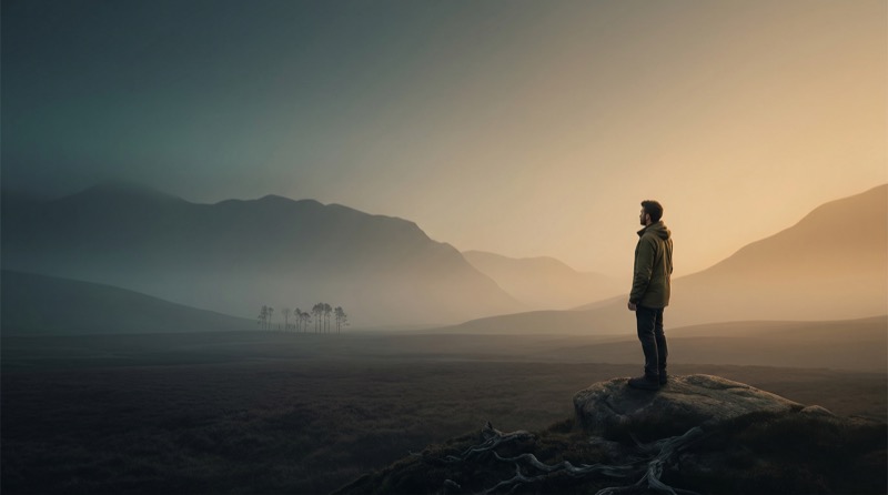 Man Standing on Rock in Misty Mountain Valley