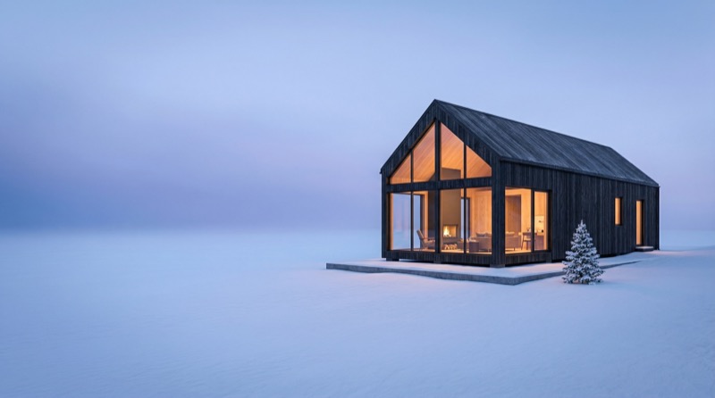 Modern cabin with warm lights in snowy landscape