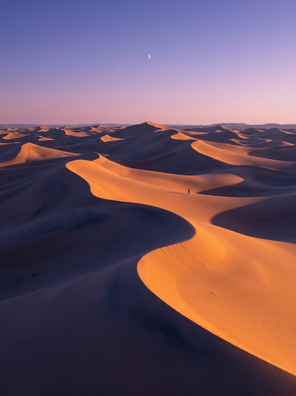 Sunlit Desert Dunes at Twilight with Crescent Moon