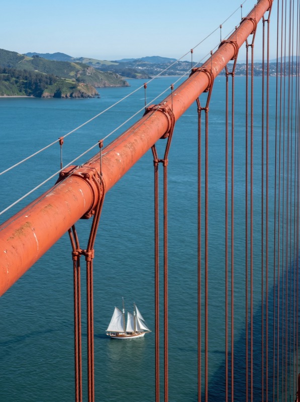 Suspension bridge cables over bay with sailboat - Image 1