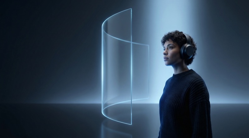 Woman with headphones beside glowing glass panel
