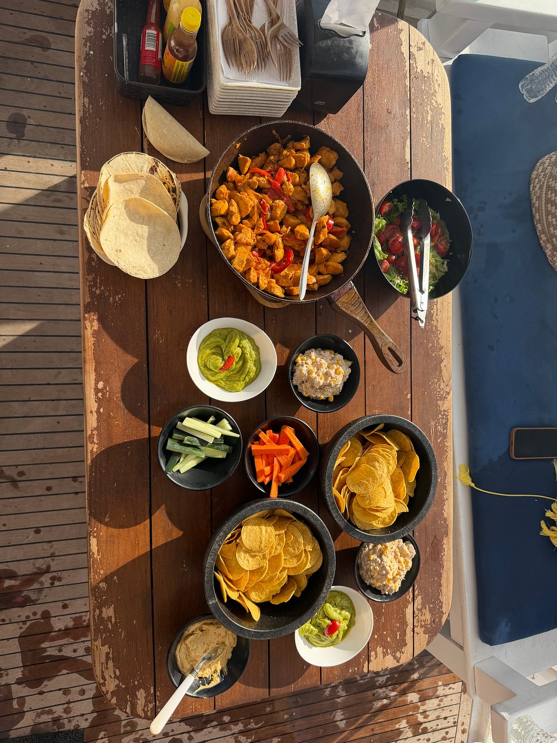 Spread of fajitas, tortillas, chips, and guacamole on the boat's table