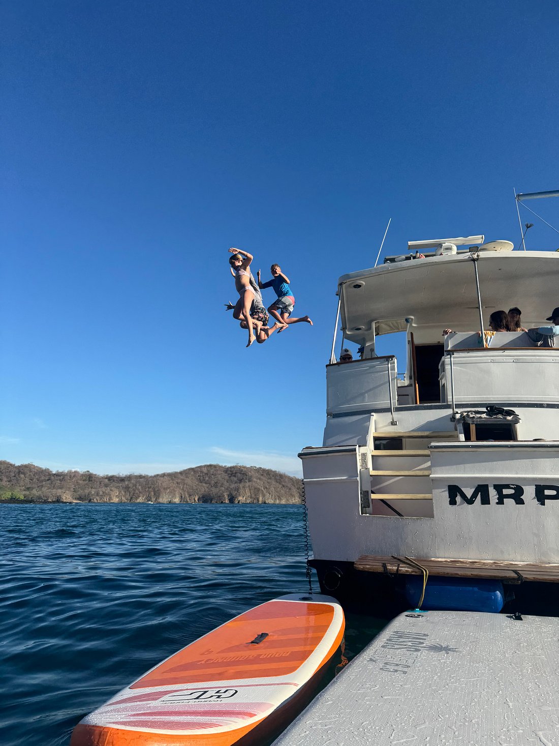 Guests jumping off the back of the Mr. Pelicano boat into the ocean