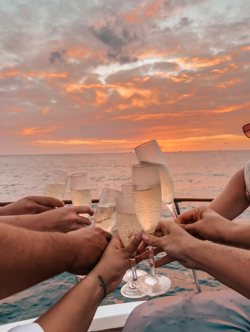 Guests toasting champagne glasses at sunset on the boat