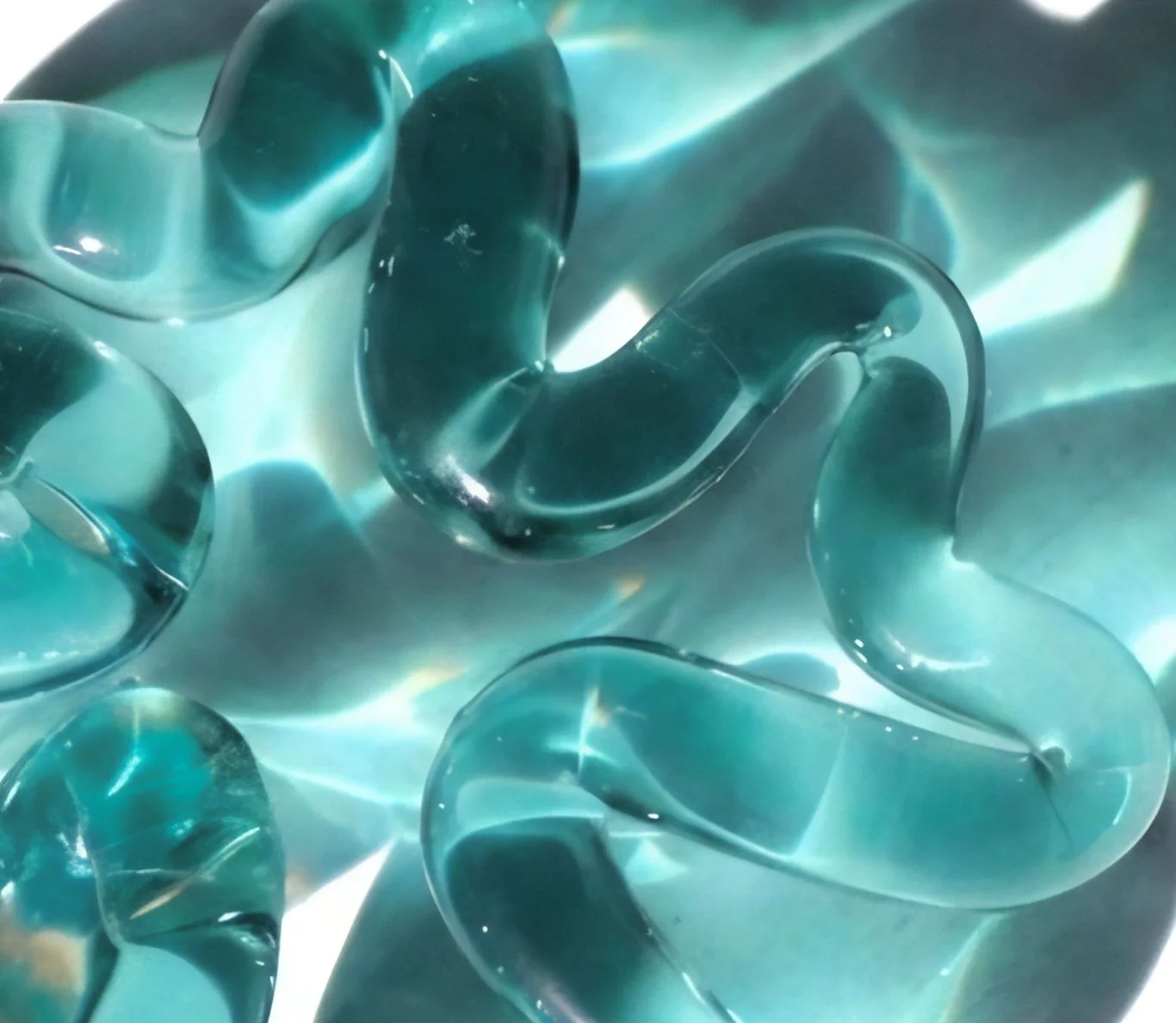 Joyas de vidrio translúcido en tonos aqua con formas orgánicas y reflejos luminosos.