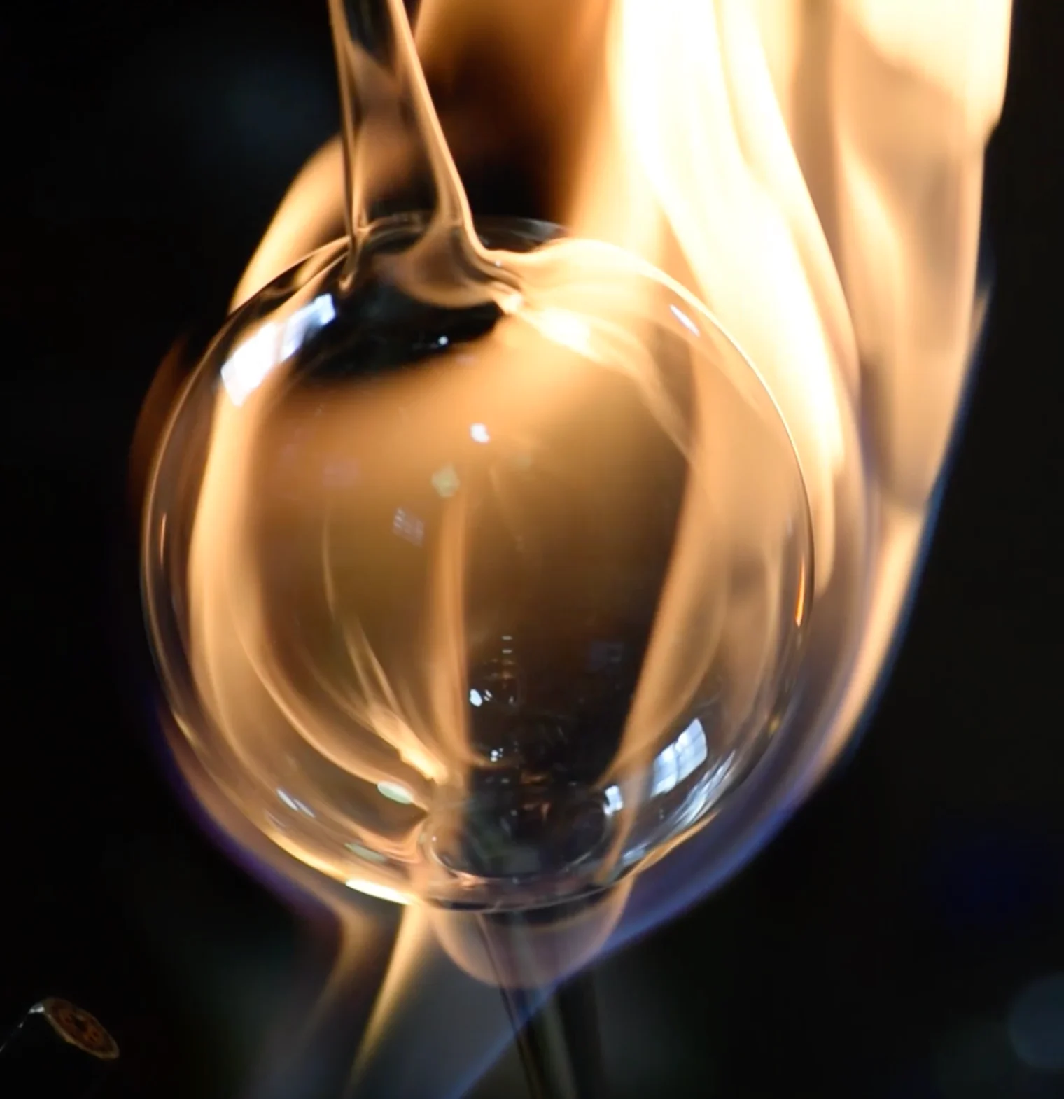 Vidrio fundido siendo moldeado con fuego durante el proceso artesanal.