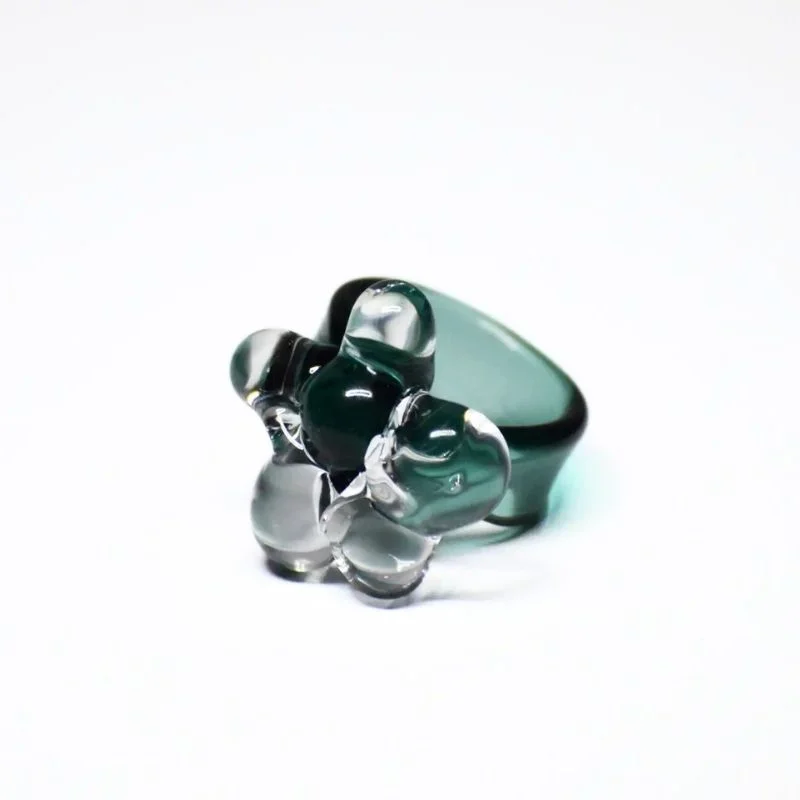 Anillo de vidrio translúcido con detalles florales y acabado brillante.
