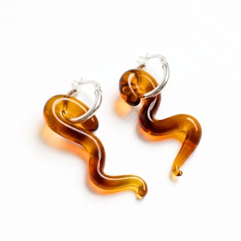 Aretes de vidrio ámbar con forma ondulada y argollas plateadas.