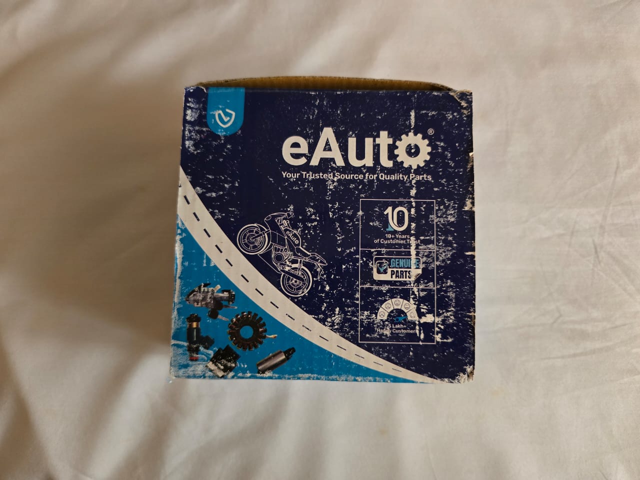 The eAuto branded outer cardboard box, featuring the eAuto logo, a tagline 'Your Trusted Source for Quality Parts,' and an impactful graphic of a motorcycle, implying a commitment to genuine parts and quality service.