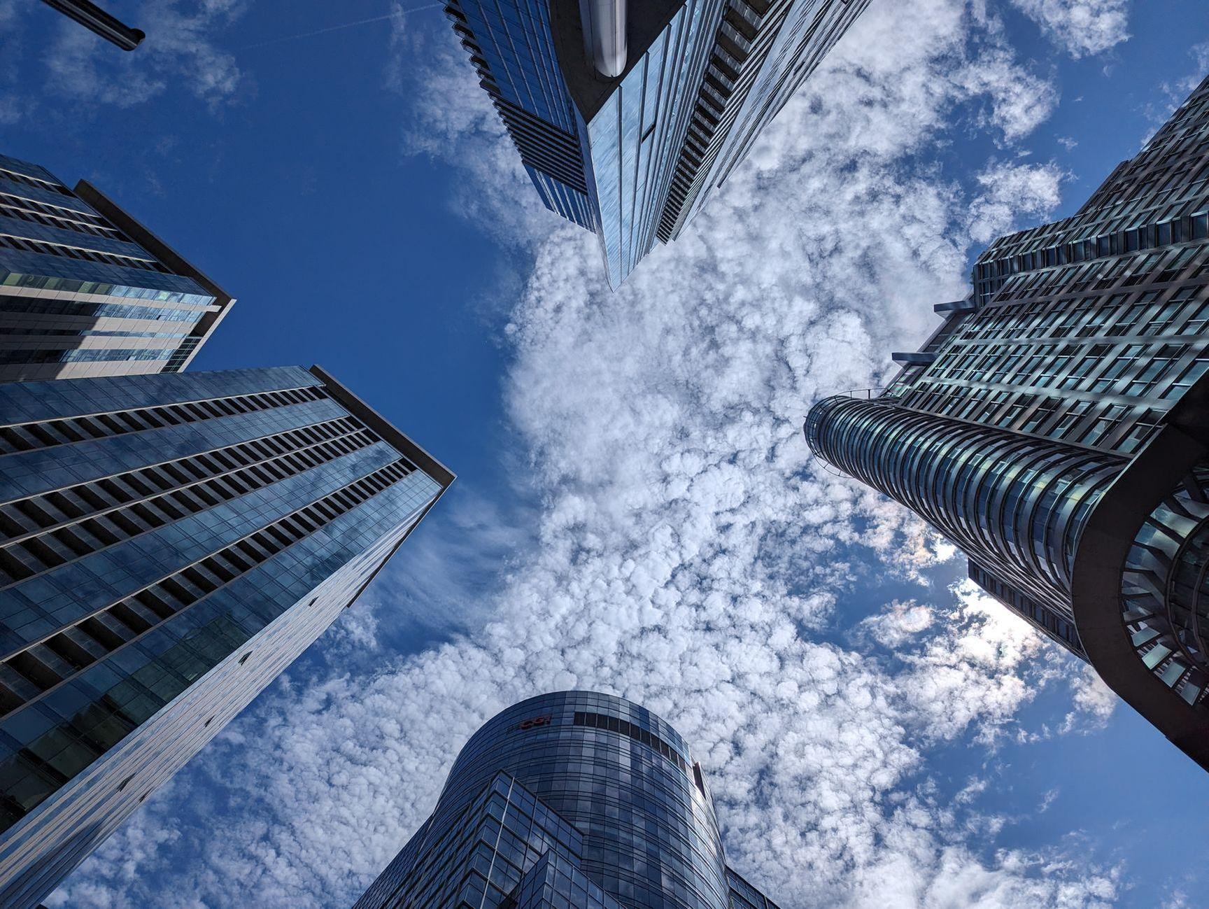 General visual reference for The Metaphor of the 'Smoke Break'. Source: Pexels / Photo by teyi 徐 / Pexels License / https://www.pexels.com/photo/clouds-in-sky-among-skyscrapers-17351599/